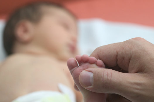 Babyfuss in großer Hand