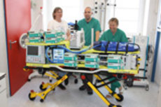 Foto einer Hubschrauberspezialtrage mit drei Personen im Hintergrund