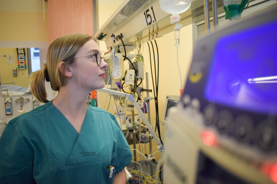 Medizinische Fachkraft in grüner OP-Kleidung überwacht medizinische Geräte