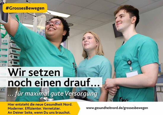 Drei Pflegekräfte in grüner Dienstkleidung schauen gemeinsam auf einen Monitor