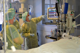 Zwei Ärzte in Bereichskleidung verschaffen sich bei einer Begehung auf der Intensivstation einen Überblick über die Behandlungsabläufe.