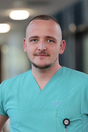 Portraitfoto eines jungen Mannes in grüner Dienstkleidung