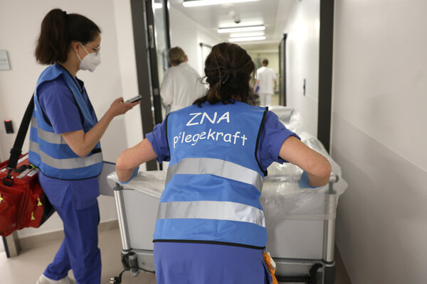 Zwei Krankenhausmitarbeiter der Notfallaufnahme schieben eine Patientin im Bett