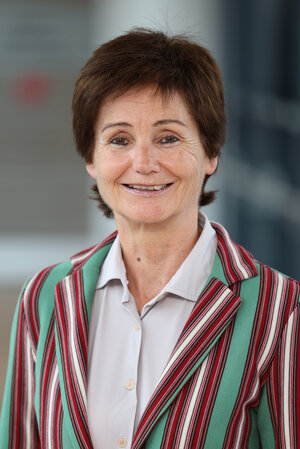 Portraitfoto Evelyn Möhlenkamp mit hellem Oberhemd und bunt gestreiftem Jackett