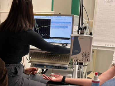 Das Bild zeigt eine Mitarbeiterin, die eine Ultraschalluntersuchung eine Gefäßes im Arm eines Patienten durchführt 