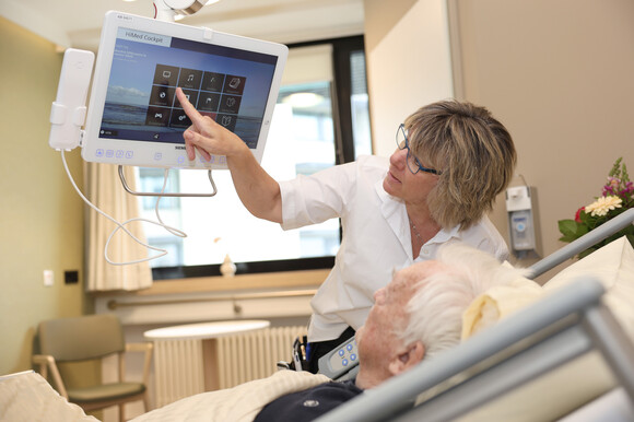 Eine Servicekraft erklärt das Patientencockpit