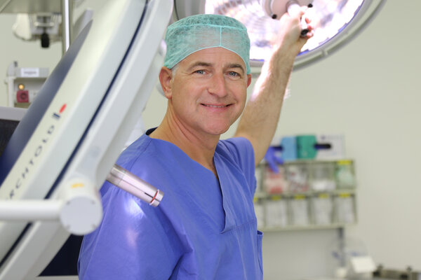 Prof. Dr. Jens Garbade im OP in Dienstkleidung und mit blauer OP-Haube