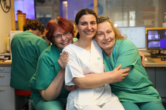 Drei medizinische Fachkräfte umarmen sich und lächeln in die Kamera