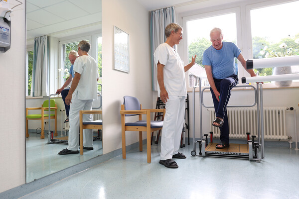 Physiotherapeut an einem Balanceboard mit einem Patienten