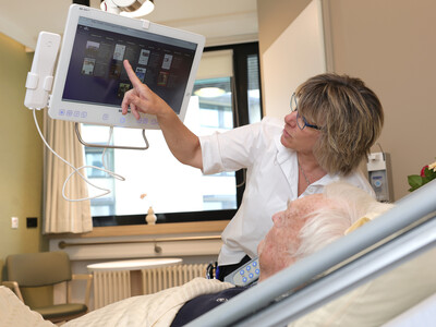 Eine Wahlleistungsmanagerin erklärt am Patientencockpit die Funktionalitäten