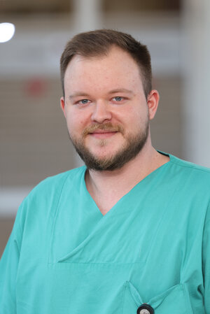 Portraitfoto eines jungen Mannes in grüner Dienstkleidung