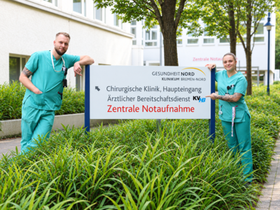 Zwei Pflegekräfte in Dienstkleidung vor dem Eingang zur Notfallaufnahme